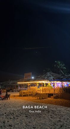 the beach is lit up at night and people are sitting in chairs on the sand