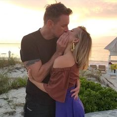 a man and woman kissing on the beach