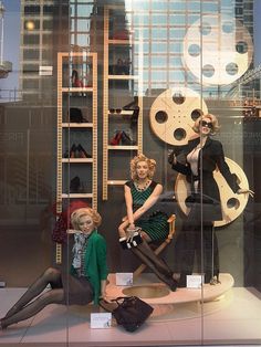 three mannequins are sitting in front of a window with film reels