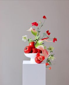 a white vase filled with lots of red and green flowers