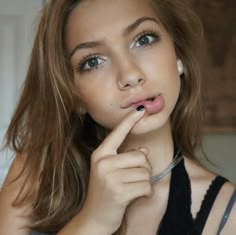 a young woman poses with her finger on her lip