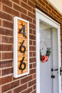 a house number sign mounted to the side of a brick building next to a door