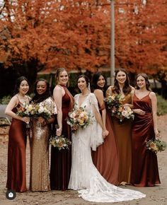 a group of women standing next to each other wearing dresses and holding bouquets in their hands