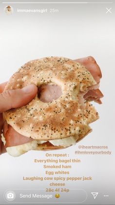 a person holding a bagel with ham and cheese