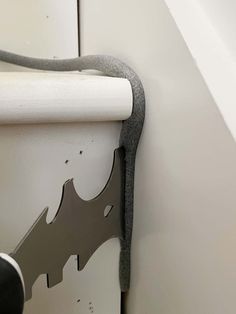 the corner of a bathroom wall with a gray and white bat on it's side