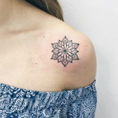 a woman's shoulder with a tattoo on the back of her shoulder and a flower in the middle