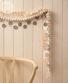 a wooden chair sitting in front of a white wall with beads hanging from it's back