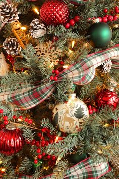 the christmas tree is decorated with red, green and gold ornaments that are wrapped in plaid ribbon