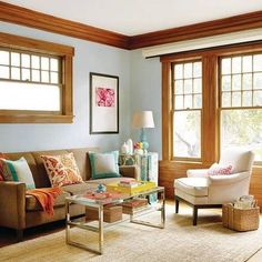 a living room filled with furniture and windows covered in wooden trimmings on either side of the couch