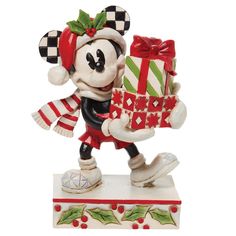 a mickey mouse figurine holding a christmas present on top of a white base