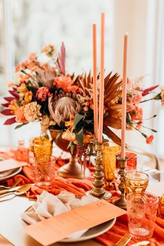 an orange table setting with candles and flowers