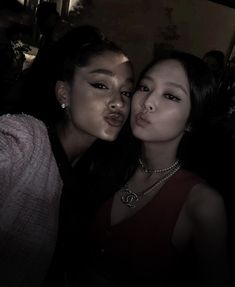 two women are posing for the camera with their faces close to one another, both wearing necklaces