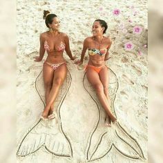 two women in bikinis sitting on the beach