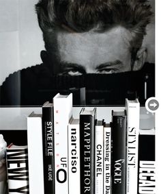 a black and white photo of a man's face behind books on a shelf