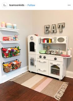 a play kitchen with white cabinets and wooden floors