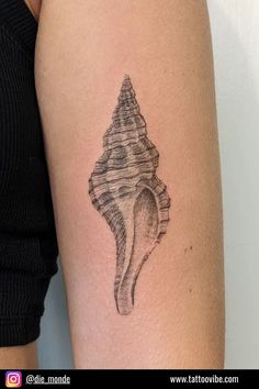 a woman's arm with a black and white sea shell tattoo on the left side