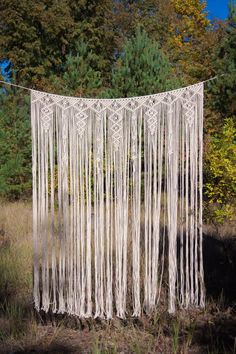 a large white macrame hanging from a line in the woods with trees behind it