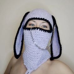 a woman wearing a crocheted bunny mask with chains around her neck and nose