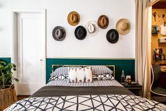 a bed room with a neatly made bed and hats on the wall