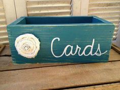 a wooden box with the word cards written on it and a white flower in the center