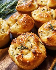 several small muffins with rosemary sprinkled on top sitting on a wooden board