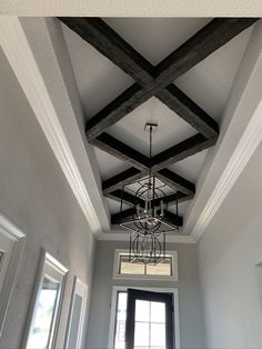 a chandelier hanging from the ceiling in a room with white walls and wood beams