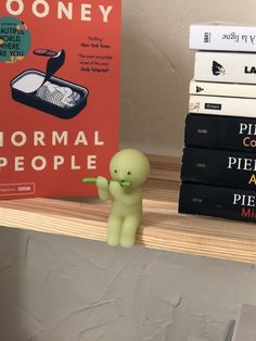 a small toy is standing next to some books on a shelf with a green alien