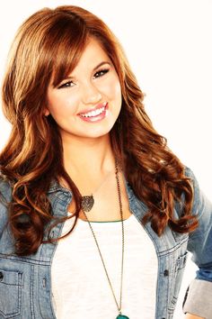 a woman with long brown hair wearing a jean jacket