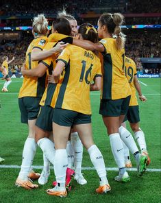 a group of women's soccer players huddle together on the field