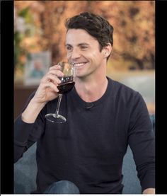 a man sitting on a couch holding a glass of wine