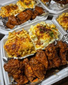 chicken wings, macaroni and cheese in tins on a table with utensils