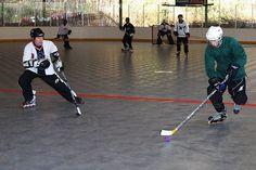 some people are playing ice hockey on an indoor court and one is holding a stick