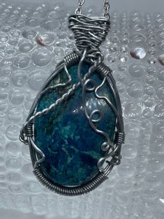 This beautifully wire wrapped Shattuckite necklace with Swarovski Crystal Accent is absolutely gorgeous! We handmade this Shattuckite Cabrochon, and wire wrapped it with stainless steel wire, then hung it on a handmade 18 inches Stainless Steel Chain with a sparkling Swarovski Crystal on the end for an added accent. This Shattuckite is gorgeous with it's variations of bright blues and greens! It will make a lovely piece for any occasion!  Shattuckite is oxidized copper deposits as a secondary, which you can find along with other copper mineral deposits like Chrysocolla and Malachite. Shattuckite is found in many locations around the world, but it's name originated from the Bisbee, Arizona Shattuckite mine where it was discovered by a Pennsylvania man named Lemuel Shattuck in 1888. Lemuel S Unique Hand Wrapped Silver Plated Wire Necklace, Turquoise Apatite Wire Wrapped Jewelry, Handmade Apatite Pendant Necklace, Artisan Wire Wrapped Chrysocolla Jewelry, Bisbee Arizona, Copper Mineral, Oxidized Copper, Stainless Steel Wire, Steel Chain