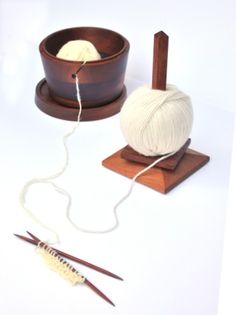 a ball of yarn sitting on top of a wooden stand next to two skewers