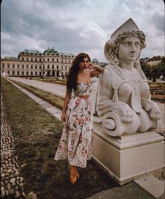 a woman standing next to a statue in front of a building