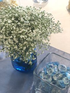 a vase filled with baby's breath flowers next to a blue container full of water