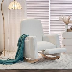 a white rocking chair with a blanket on it