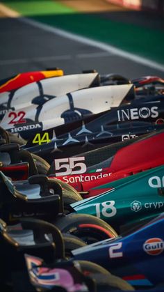 a row of racing cars sitting on top of a race track next to each other