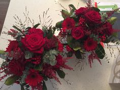 two vases filled with red flowers sitting on top of a white table next to each other