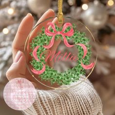 a hand holding a christmas ornament with the name mimi on it and a pink bow