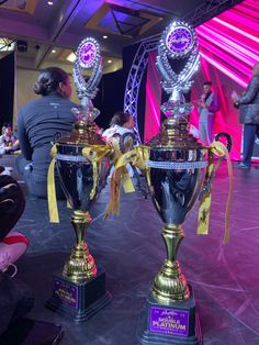 two large trophies sitting on top of each other in the middle of a floor covered with people