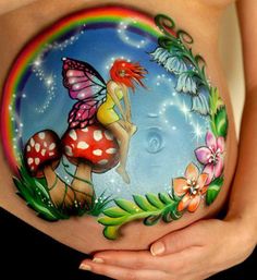 a pregnant belly painted with flowers, butterflies and a fairy sitting on top of it