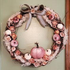 a wreath with pink flowers and an orange pumpkin