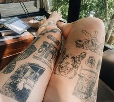 a woman's legs with tattoos on them sitting in front of a desk and window