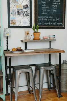 two metal stools sitting under a wooden table