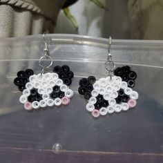 a pair of earrings with black, white and pink beads