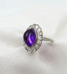 The Amethyst pendant in the video was a separate listing/has sold. Independent Written Appraisal Value:  $6,200.00 Circa 1920.  Stunning, ethereal. Luminescent Cabochon Amethyst (approximate 6.0 ctw) Surrounded by 16 Round Old European cut diamonds (approximately 1.44 ctw). This ring definitely has a presence that is truly special.  The Amethyst cabochon color and saturation faces up differently depending how it is viewed.. Just lovely. The surrounding diamonds give it a gorgeous sparkle.   Last Formal Fine Jewelry Gemstone Cabochons, Formal Fine Jewelry Cabochon Gemstones, Fine Jewelry Cabochon Gemstones For Formal Occasions, Luxury Formal Cabochon Amethyst Ring, Luxury Amethyst Cabochon Ring For Formal Occasions, Luxury Formal Amethyst Cabochon Ring, Luxury Round Cabochon Amethyst Ring, Fine Jewelry Multi-stone Cabochons As Gift, Luxury Purple Cabochon Amethyst Ring