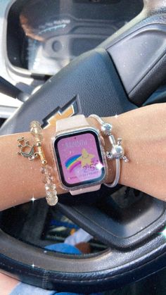 a person wearing a watch and bracelets on their wrist in a car steering wheel