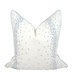 a white pillow with blue dots on the front and back of it, sitting on a white surface