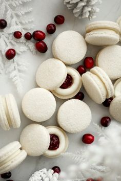 white macaroons with cranberry filling on a plate next to snowflakes